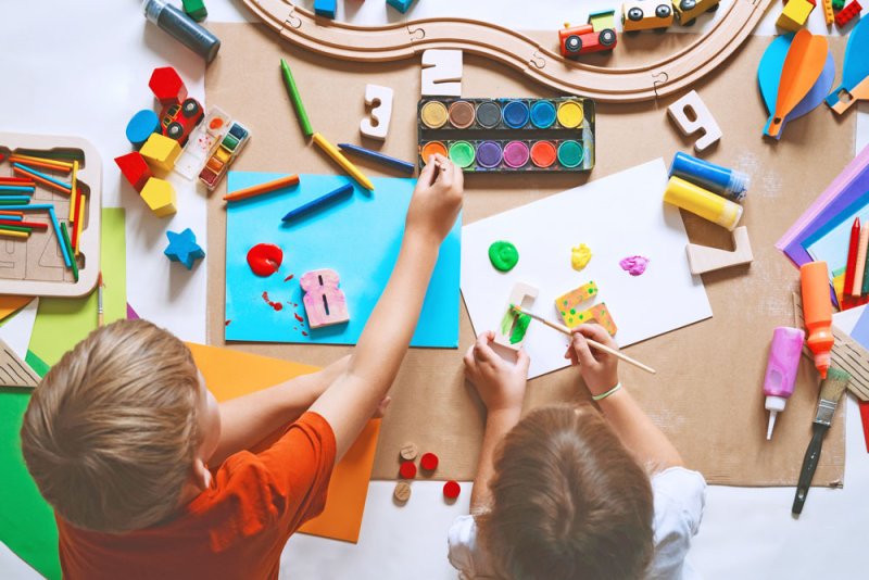 2 Kinder basteln auf gro&szlig;em Tisch &ndash;&nbsp;Ansicht von oben